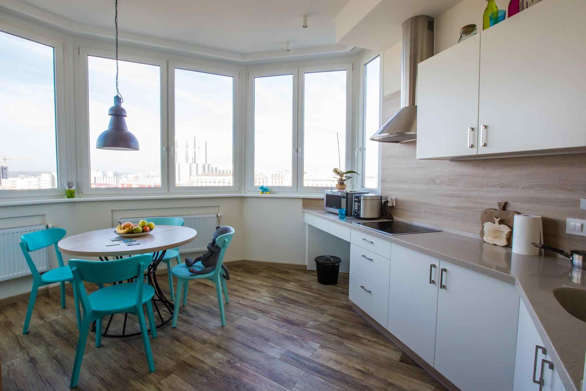 A kitchen with white cabinets and blue chairs.