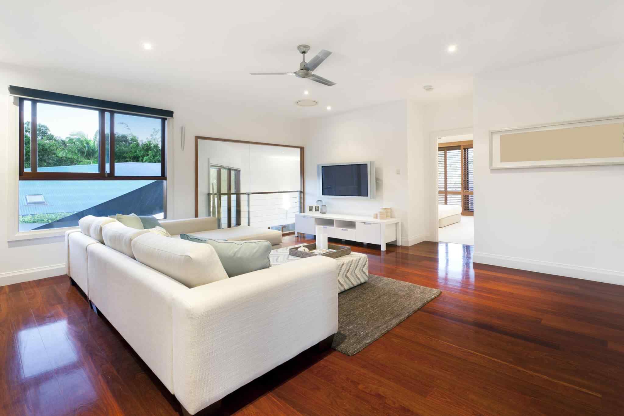 A living room with hardwood floors and white furniture.